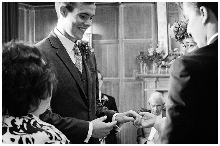 smiling groom about to exchange wedding bands with bride