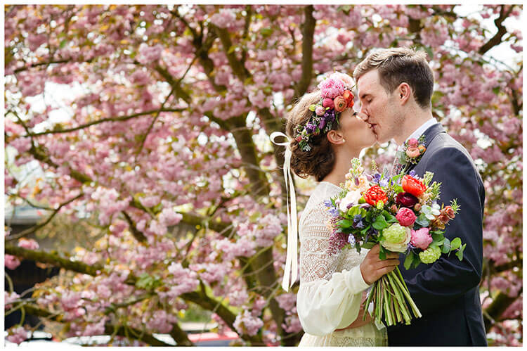 bride groom kiss infront of blossom tree at old bridge hotel