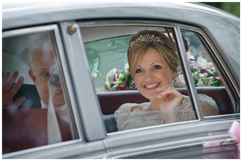 smiling bride arrives in car waving