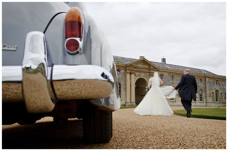 groom hold brides veil as they walk away from car at woburn sculpture gallery 
