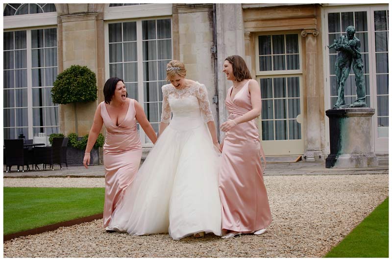 bride and bridesmaids walk and laugh in gardens of woburn sculpture gallery 