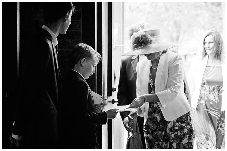 churchill college wedding usher hands order of service to guest