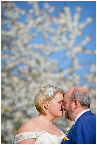 churchill college wedding bride groom embrace in front of white blossom