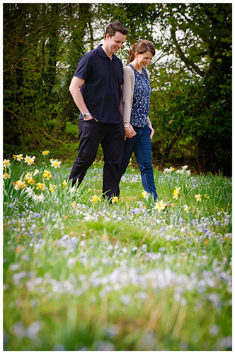 Fanhams Hall pre-wedding couple walking in filed of wild flowers