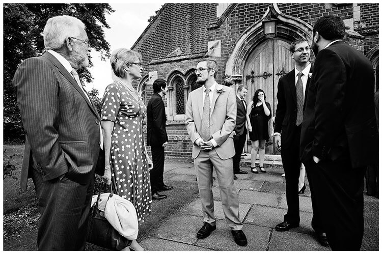 Groom talking to guests outside St John the Evangelist Church cambridge