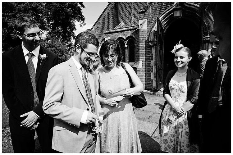 groom with guests out side St John the Evangelist Church cambridge