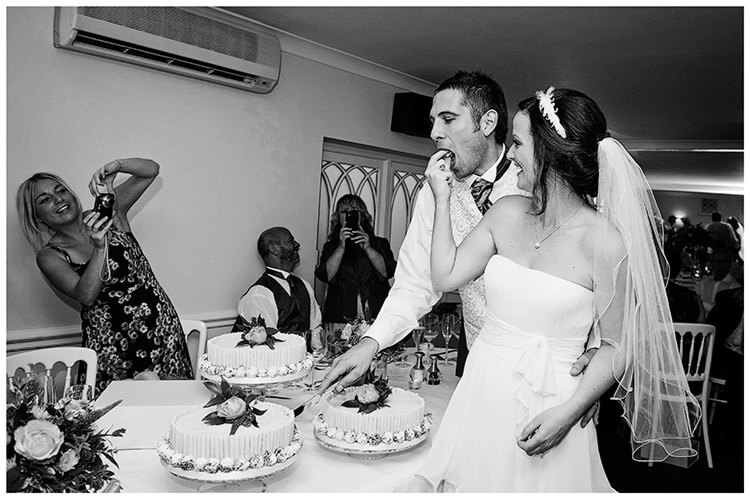 Sheene Mill wedding bride feeds a piece of cake guest takes photo