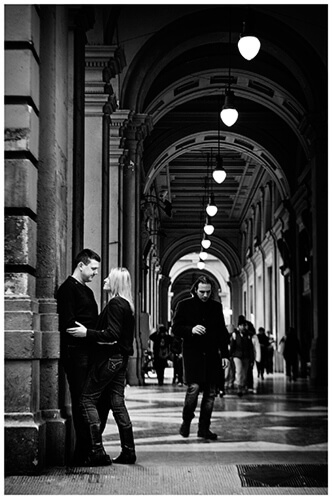 Pre-Wedding Photography in Florence couple embrace in portico as people pass