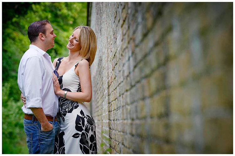 Pre-Wedding Photography shoot in Cambridgeshire couple laugh during embrace next to old wall