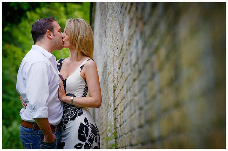 Pre-Wedding Photography shoot in Cambridgeshire couple kiss and embrace next to garden wall
