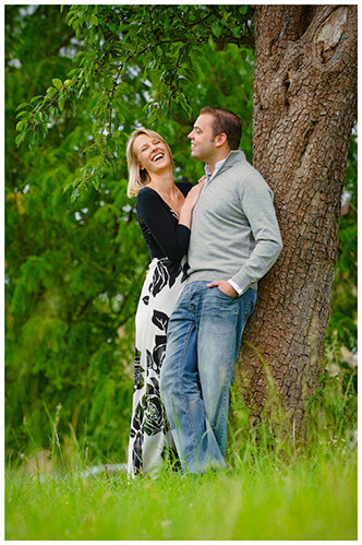 Pre-Wedding Photography shoot in Cambridgeshire laughing couple leaning against tree