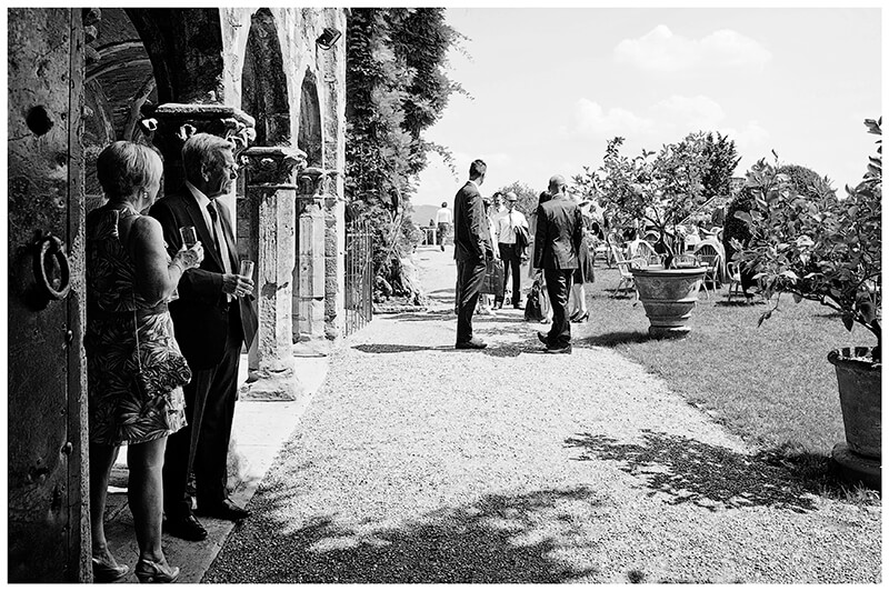 couple enjoying gardens and drink standing in shade from hot sun at Castello di Vincigliata wedding