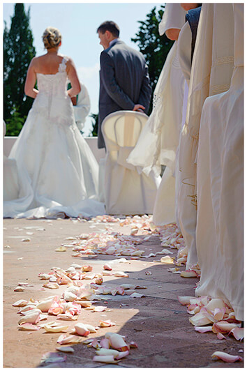 rose petals on ground with bride and groom in background during ceremony