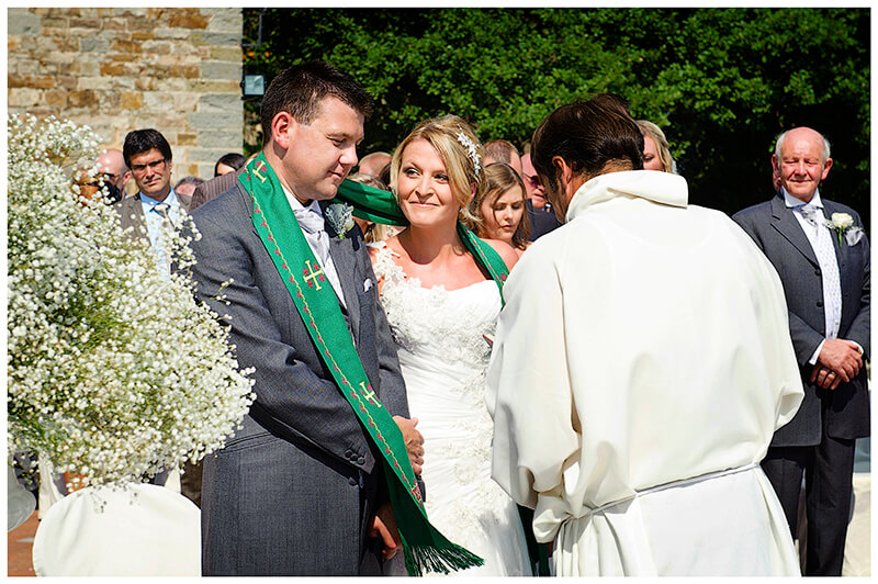 Bride groom are drapped with green sash during blessing