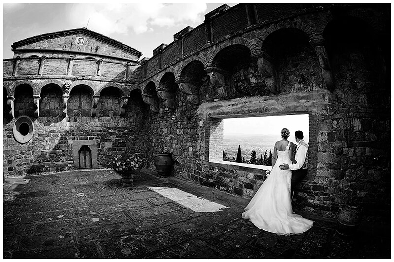 bridal couple looking out across tuscan countryside from castle tower