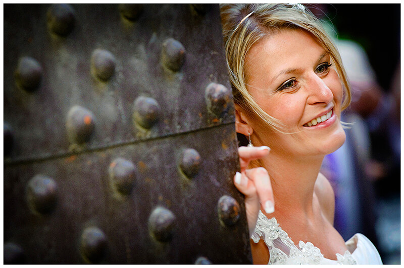 smiling bride leaning against metal door unposed portrait