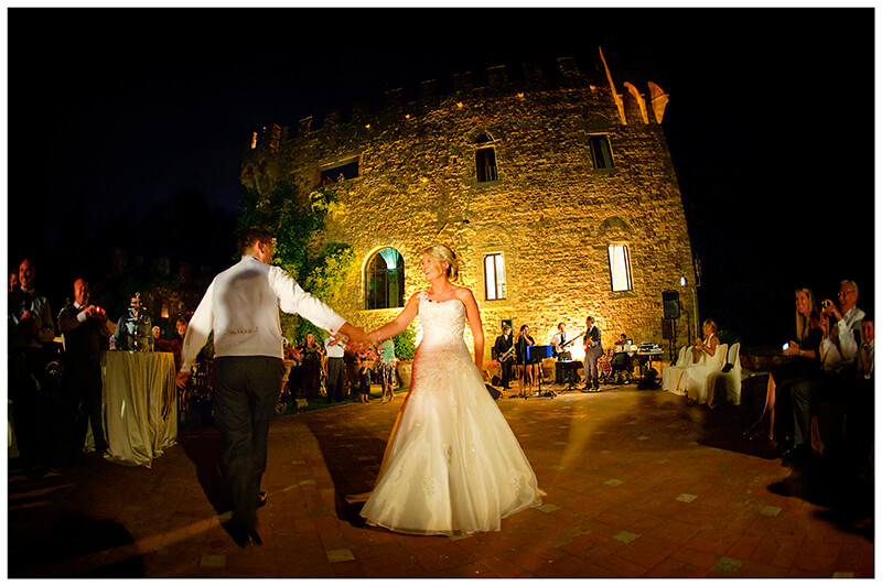Castello di Vincigliata in background as the bridal couple have their first dance as guests watch