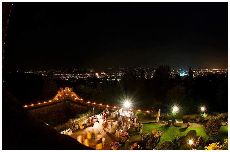 Castello di Vincigliata wedding venue at night viewed from the tower over looking the outside dance floor and Florence in the distance