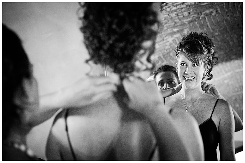 smiling bride has necklace fitted reflected in mirror