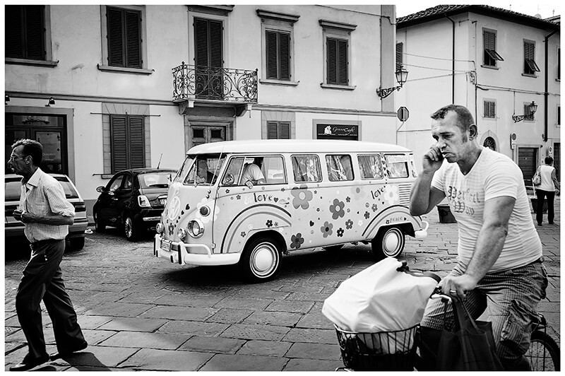 decorated Vw Camper Van as wedding car in Italian Piazza as people pass by