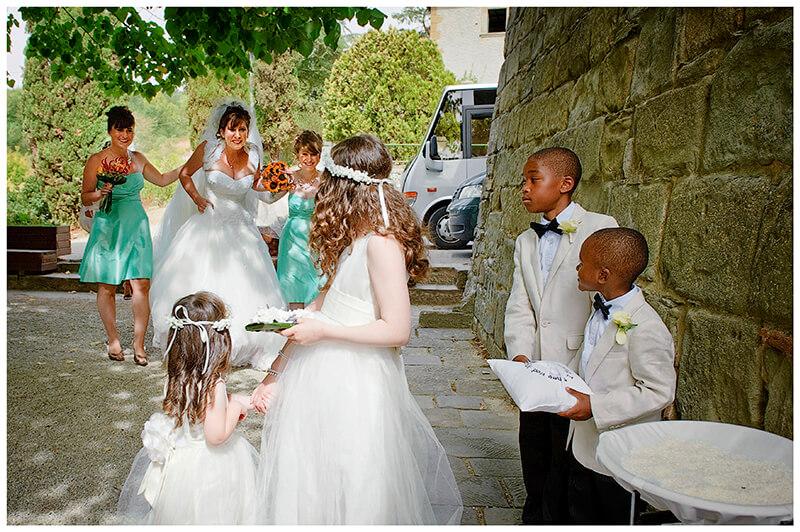Bride is greeted by paige boys and flower girls at Fraternita di Romena church Tuscany 