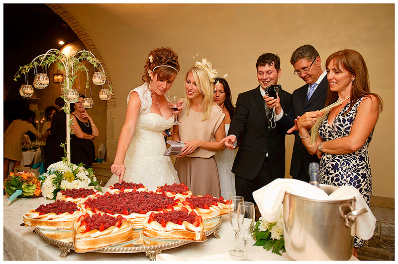 Bride groom and guests looking at wedding cake 