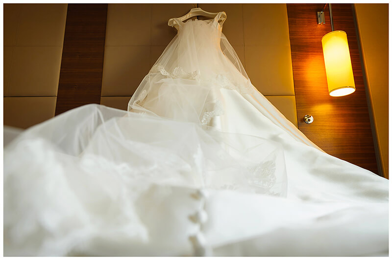 wedding dress hung on bed