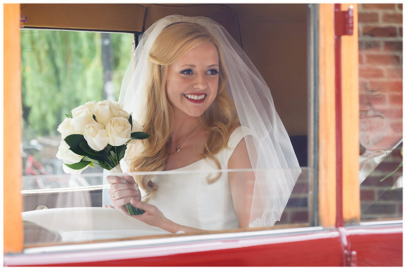 smiling Bride holding bouquet sat in car 