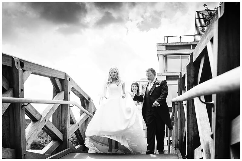 Bridal party walking over The Mathematical Bridge at Queens College Cambridge