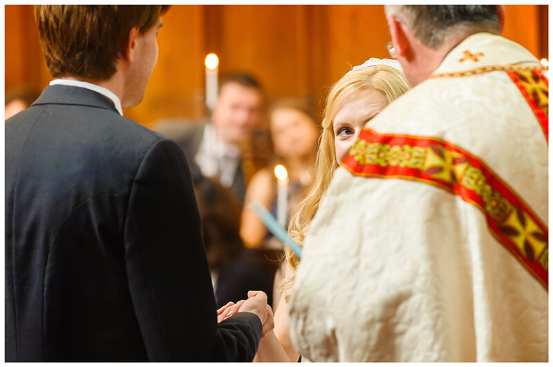 Bride looks at vicar during Queens College chapel wedding ceremony