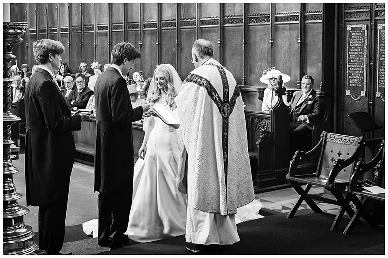 Groom places ring on brides finger in Queens College chapel