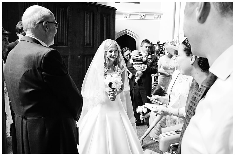 bride talking to guests in entrance to chapel Queens College wedding Cambridge