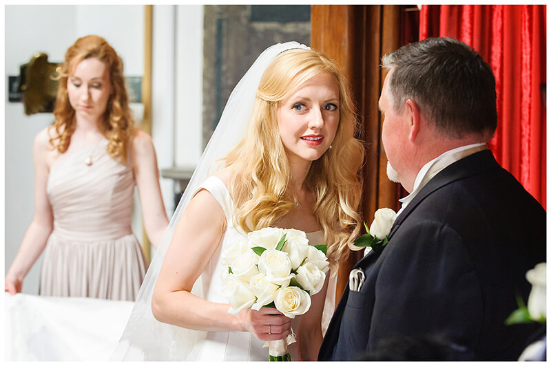 Bride talking to father in entrance to Queens College chapel 
