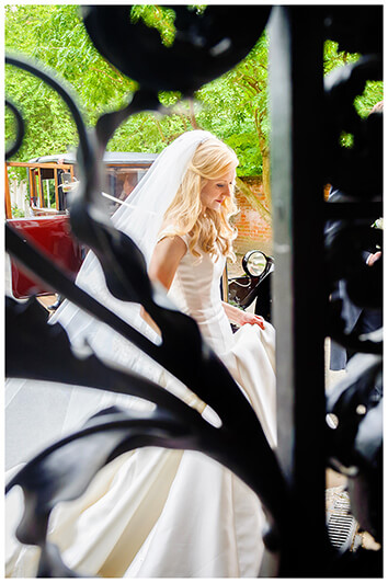 Bride viewed through gate as she arrives at Newnham College Cambridge