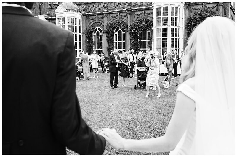 Bride groom holding hands are recieved by guests at Newnham College Cambridge