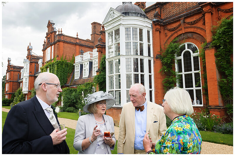 wedding guests enjoying conversation and drinks on the lawns of Newnham College Cambridge