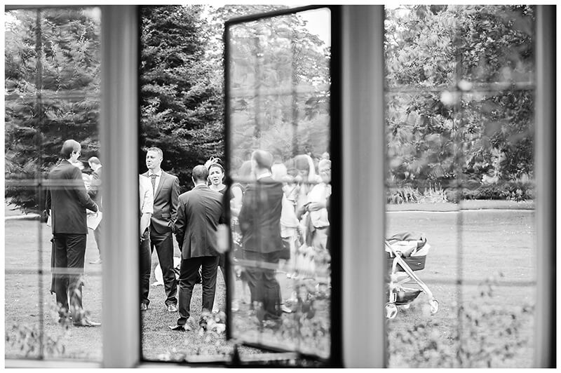 wedding guests viewed through window Newnham College Cambridge