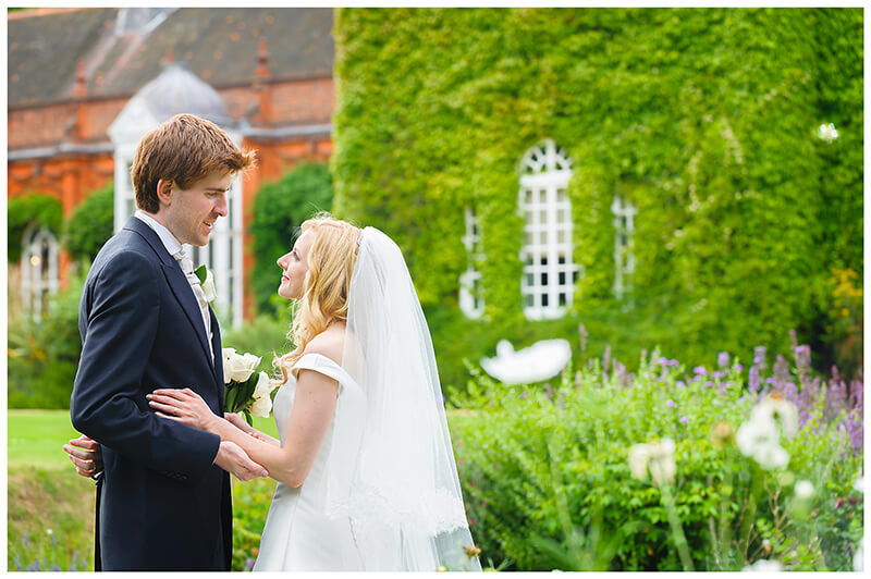 bride and groom share a private moment in amongst the flowers of Newnham College Cambridge