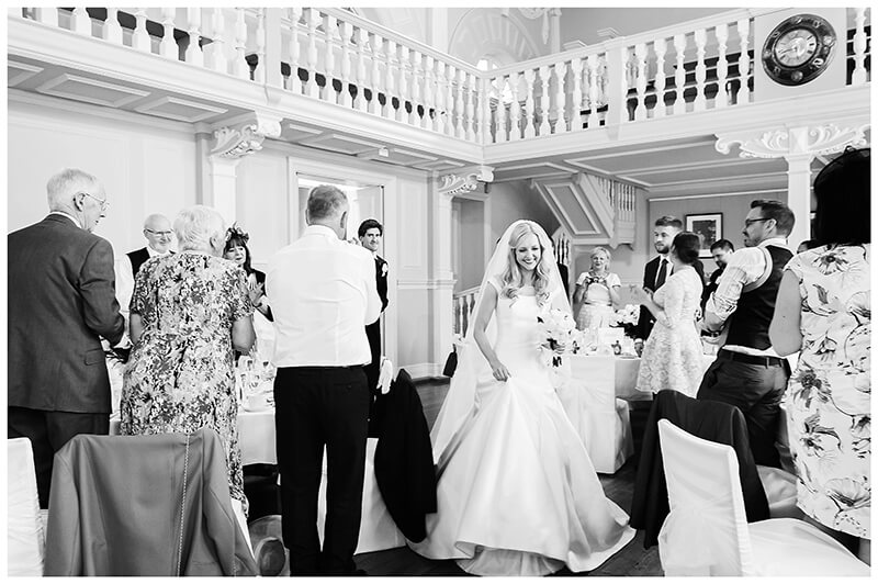 bride groom walking through applauding guests in the dining room of Newnham College Cambridge