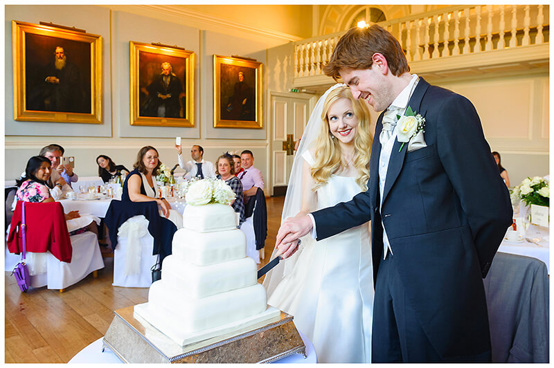 bride groom cutting cake watched by guests Newnham College Cambridge