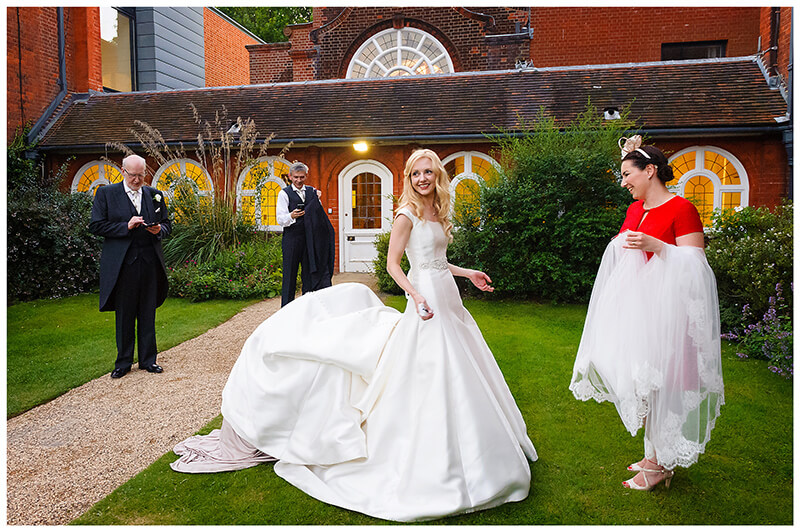bridesmaids under brides dress in gardens of Newnham College Cambridge