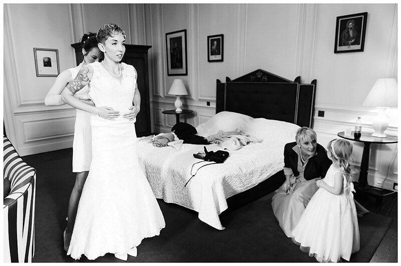 Trinity College wedding getting ready bridesmaid helps bride into dress Brides mother and flower girl watch