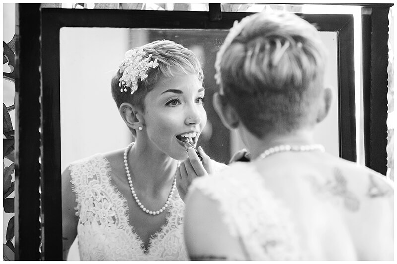bride applying lipstick in mirror