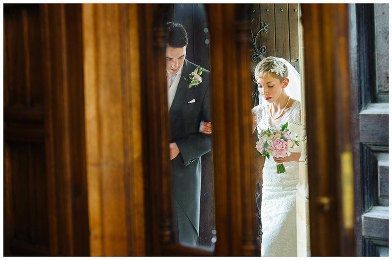bride and escort framed in door windows as they enter Trinity College chapel