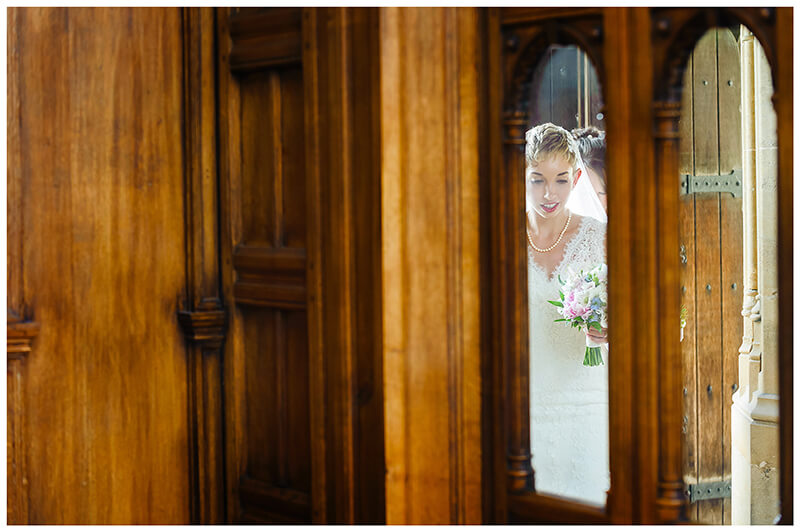 bride framed in door window as she enters Trinity College chapel