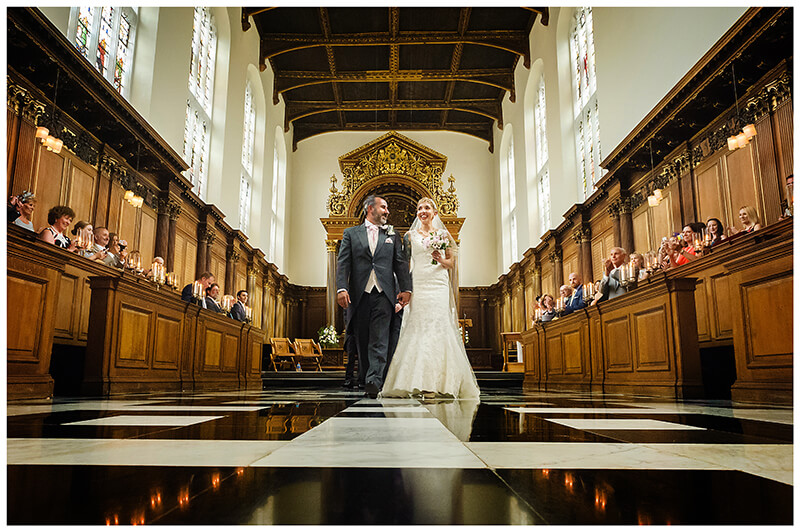 bride groom smiling walking down Trinity College chapel aisle after ceremony
