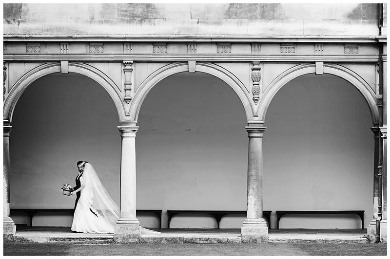 bride and groom walking past arches