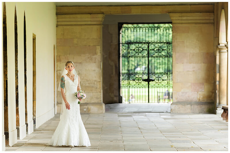 bride standing in front of iron gate in Trinity College cambridge