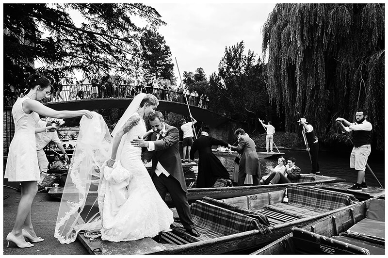 bridesmaid holds brides veil as groom helps her get on to punt