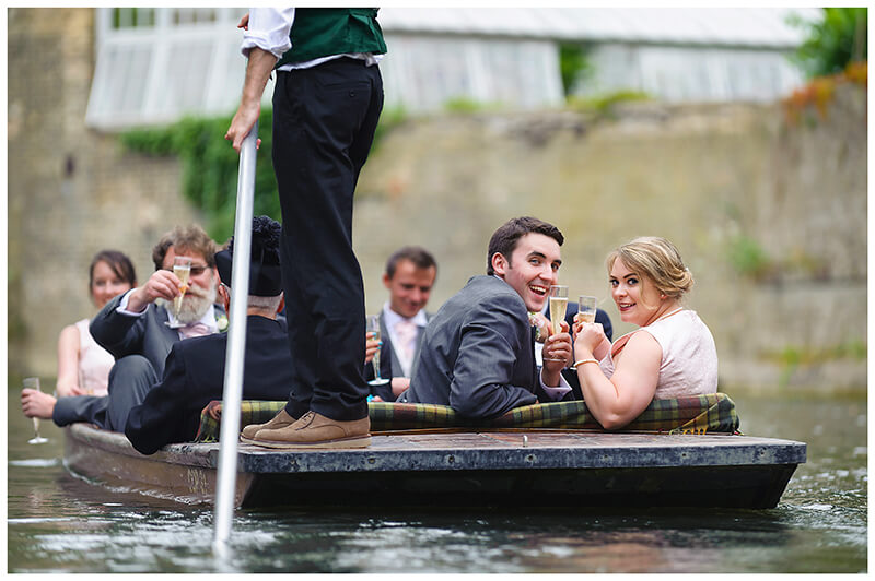 Wedding guests on a punt looking back drinking champagne